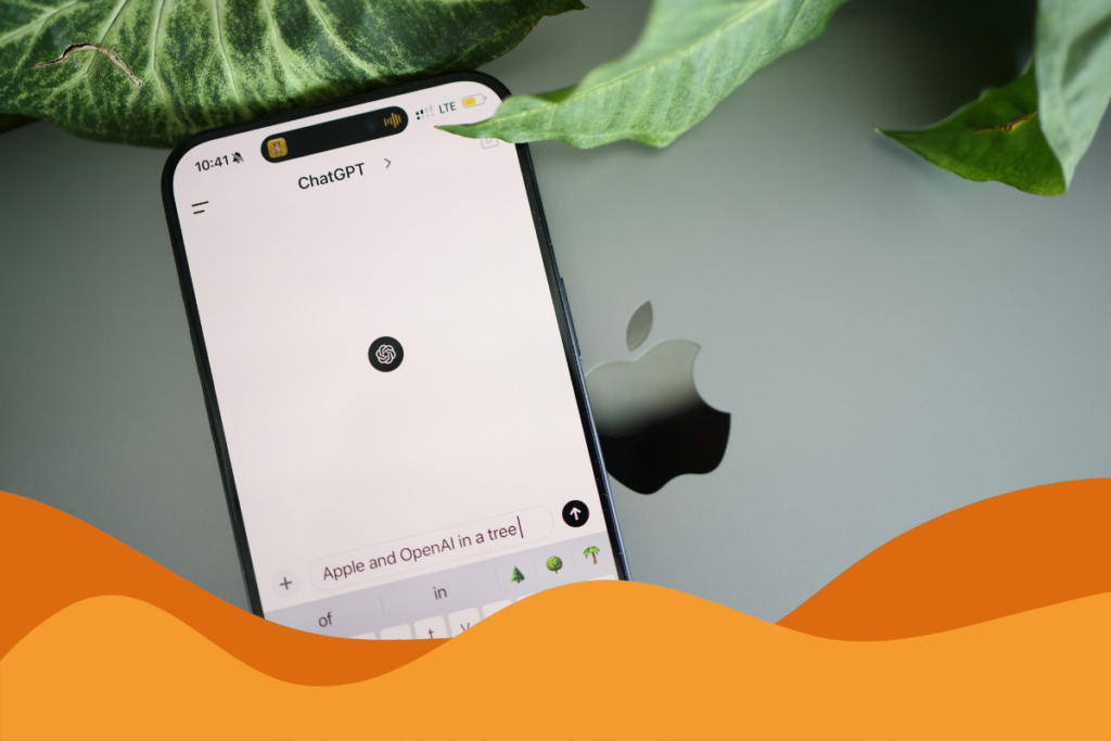 Image of an iphone on top of a macbook with chatgpt main screen on the phone, image is framed by few plants in an article about OpenAIs ChatGPT-5.2 update