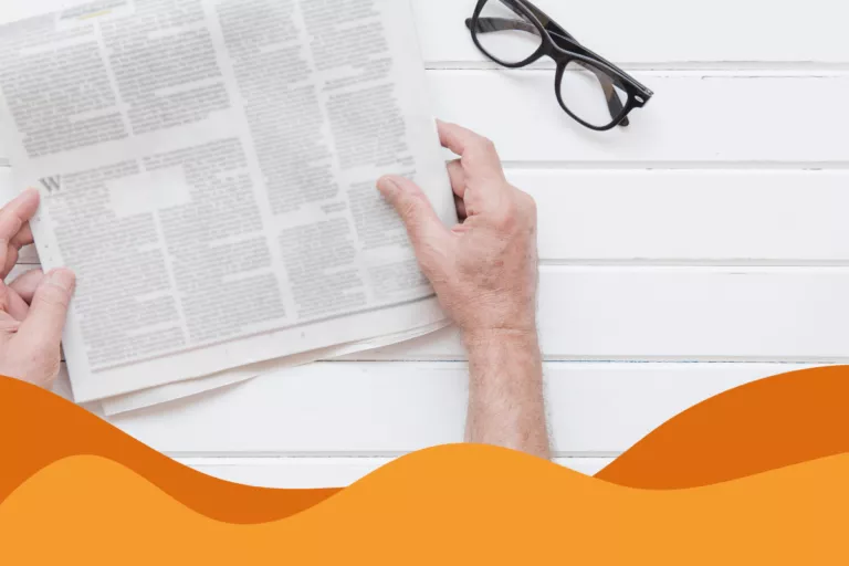 Image of a man reading a white newspaper on a white panelled surface with black glasses next to him in an article of Daffodil IT news roundup