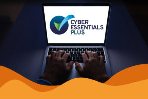 Image of cyber essentials plus logo on a white laptop screen in a dark room with someone typing on the laptop in an article announcing that Daffodil IT are now cyber essentials plus certified, in Sheffield, South Yorkshire.