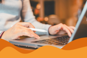 Image of a woman typing on a laptop with an Apple pen in her hand and light ambient lighting behind her in an article about how to choose the right IT service provider for your business in Sheffield by Daffodil IT in South Yorkshire